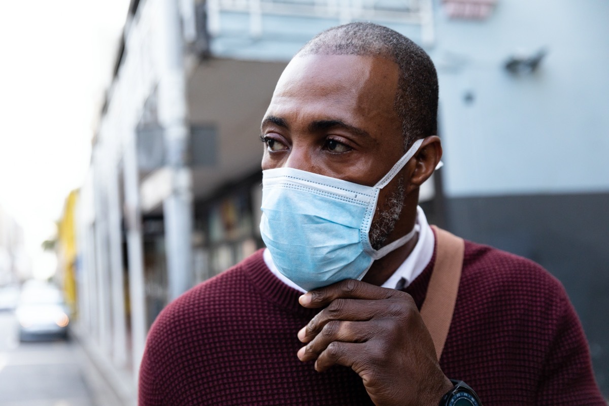 middle aged black man outside adjusting his surgical face mask amid the coronavirus pandemic