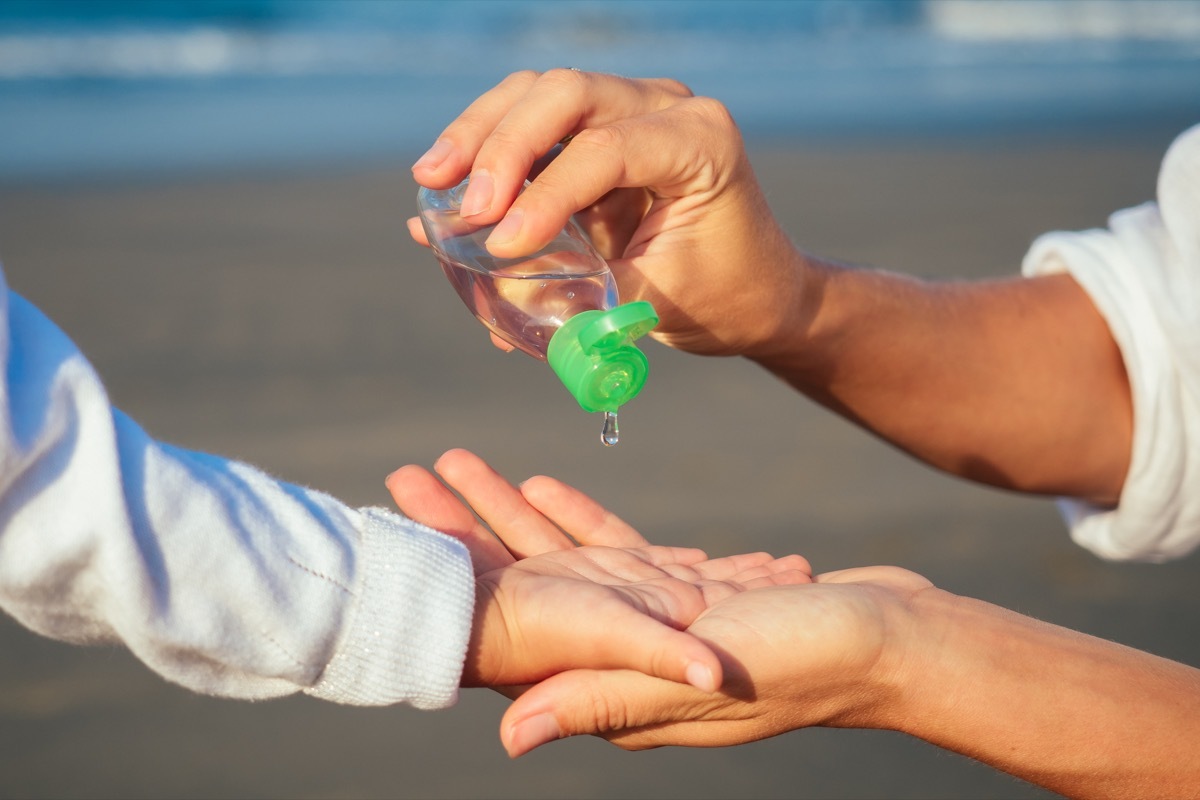 Mom Giving Her Child Hand Sanitizer on the Beach bad parenting