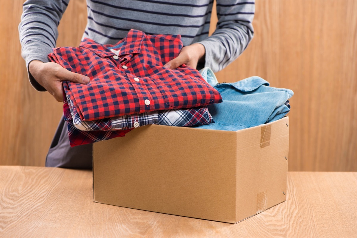 man putting clothing in cardboard box