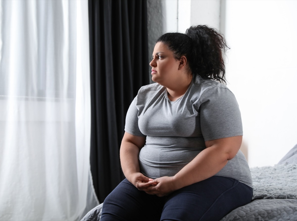 Depressed overweight woman on bed at home