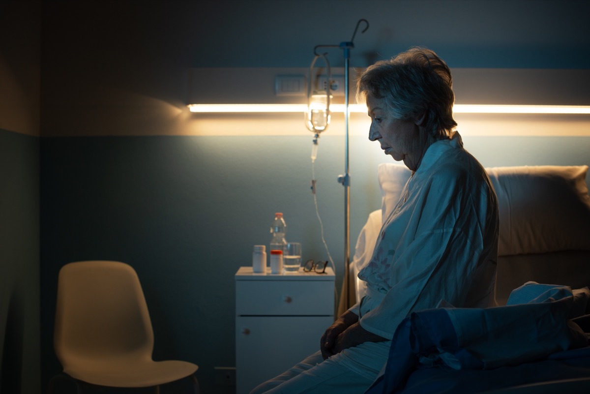 Woman sitting on the edge of a hospital bed confused