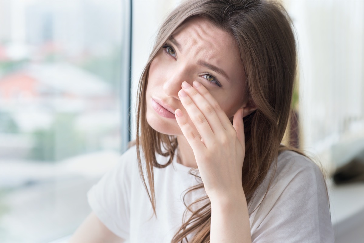 Young sad woman sits alone front of the window