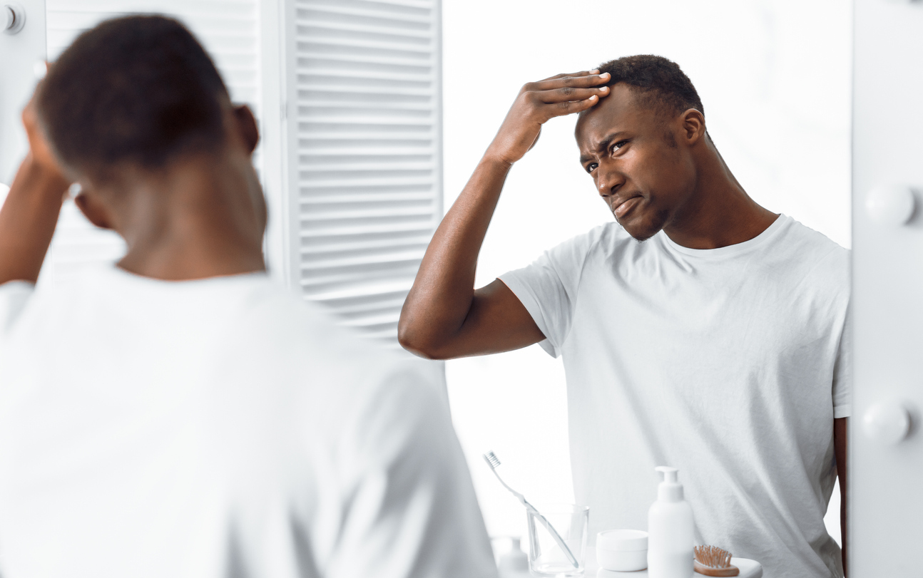 Man looking at his hair in mirror.