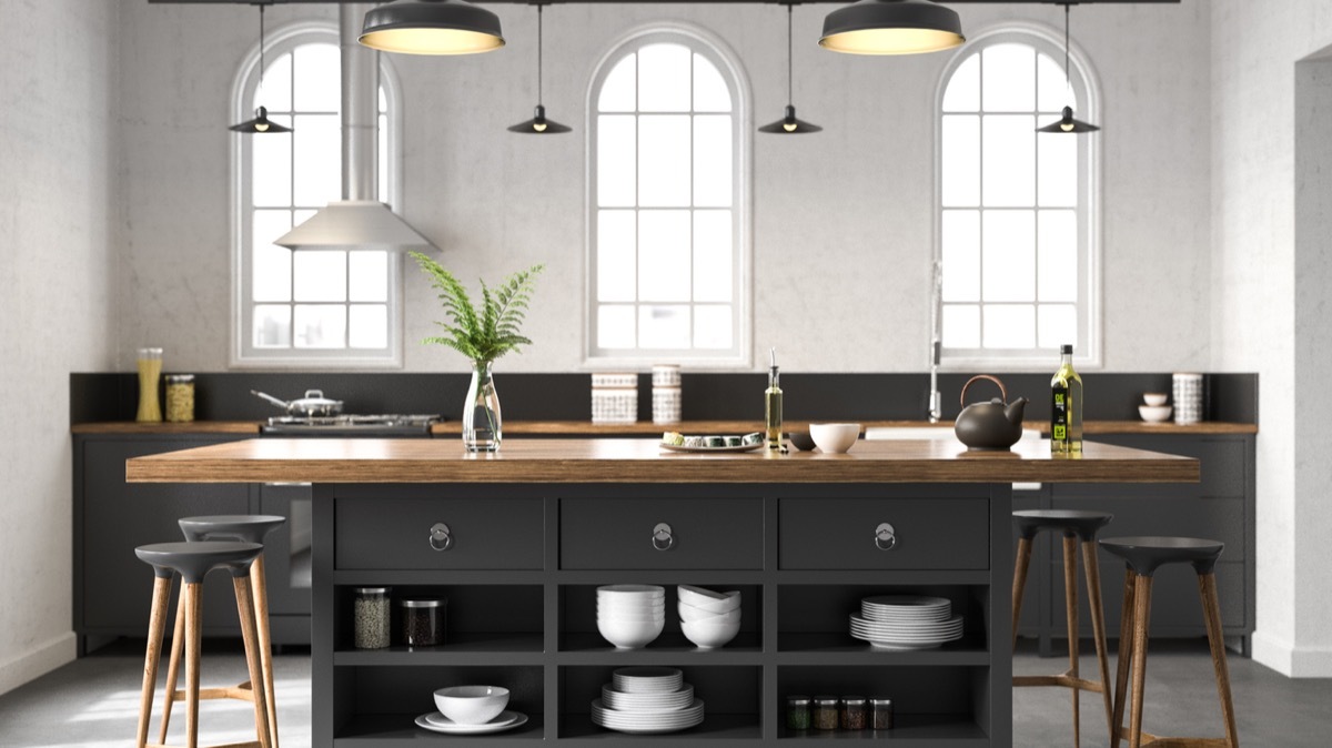 modern kitchen with black island with butcher block counters and pendant lighting