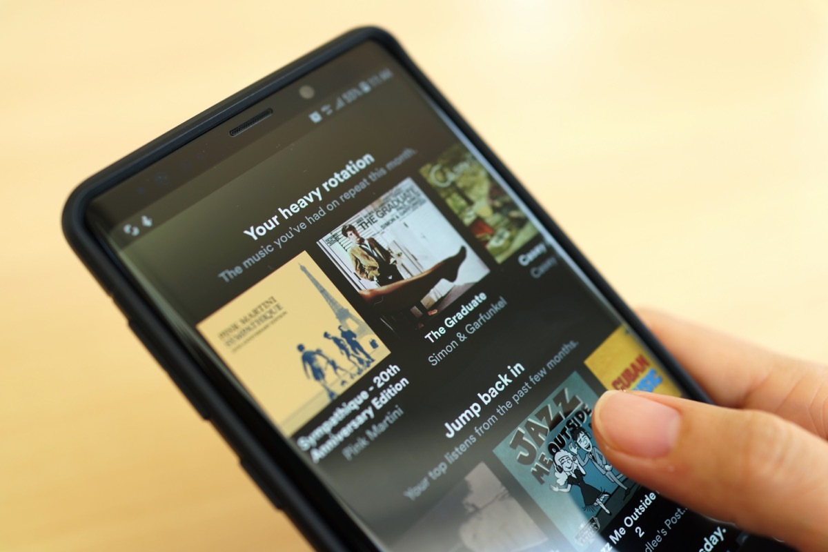 Close up woman holding Smartphone and using Spotify application on the screen