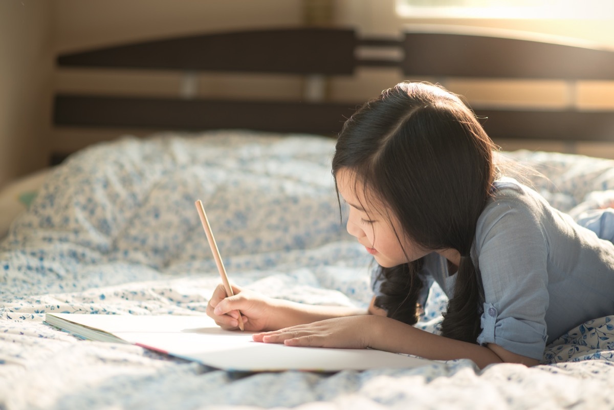 Young girl journaling on bed