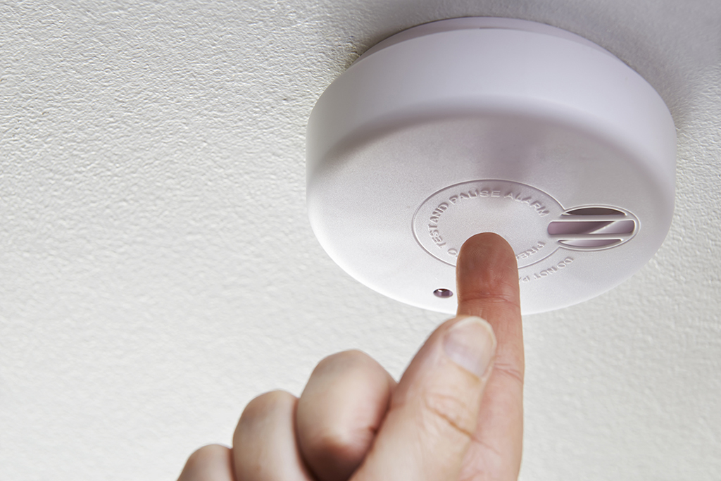 man testing white smoke detector