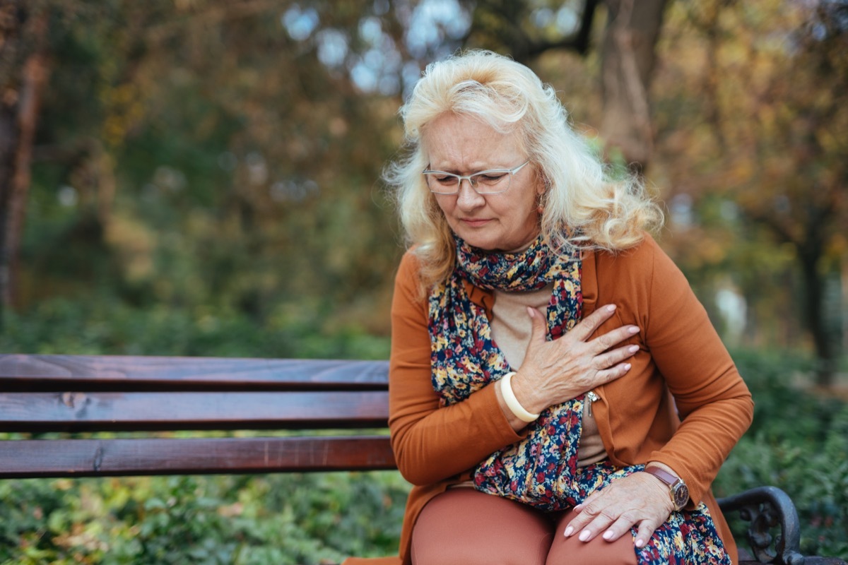 Elderly woman having chest pains or heart attack in the park