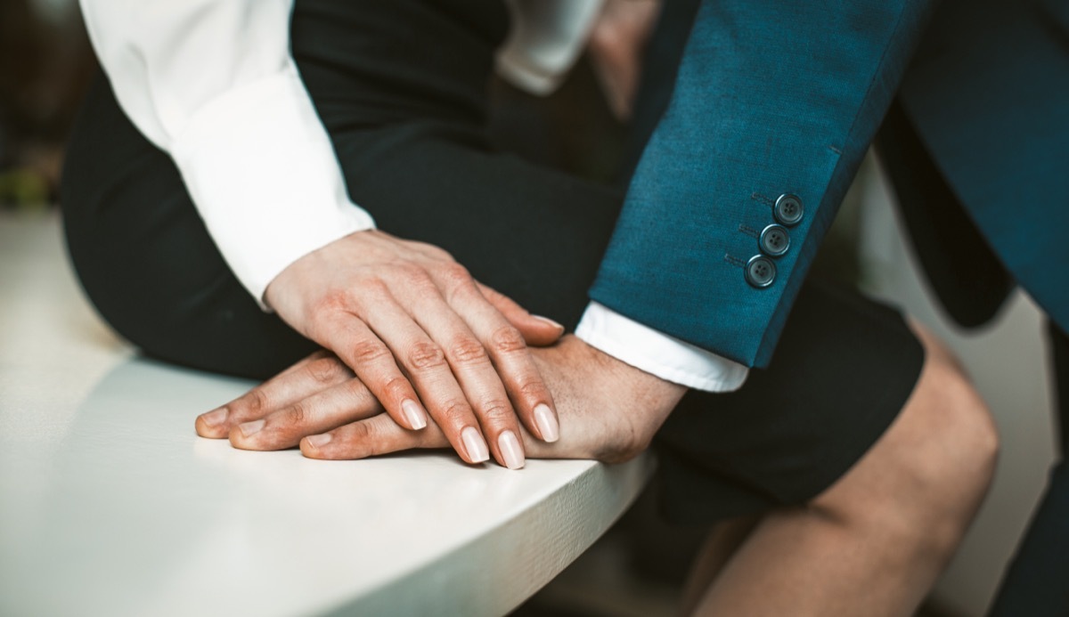 affair in the workplace, cropped image of a man leaning in towards a woman sitting on a table