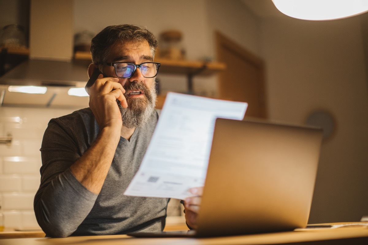 Mature men at home during pandemic isolation reading something on laptop