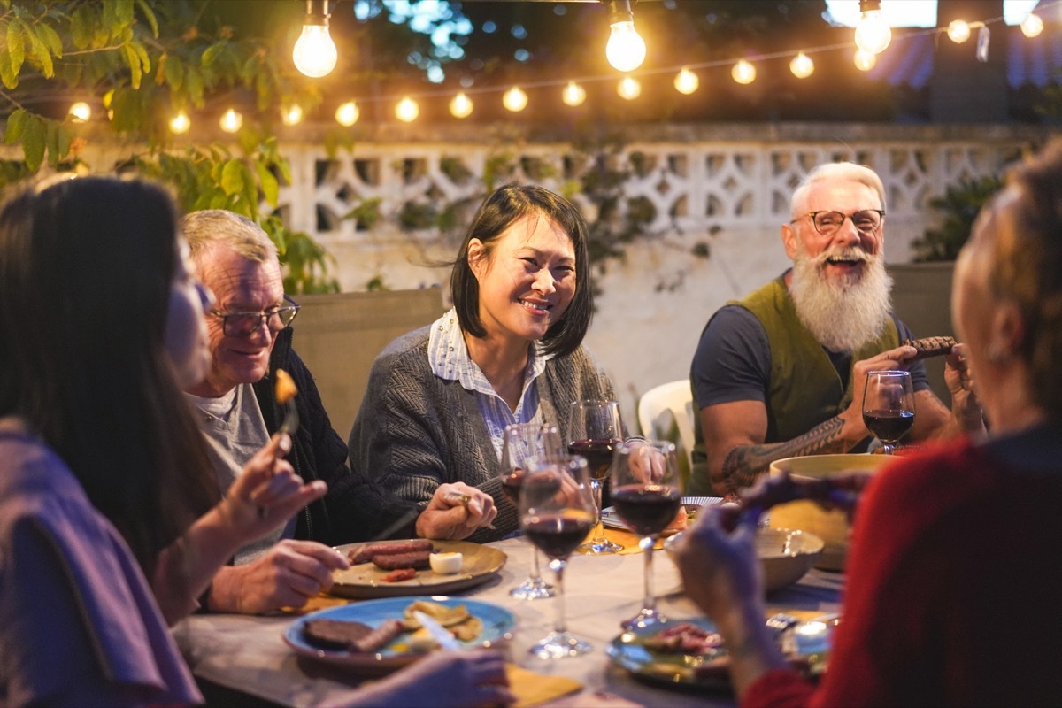 group of friends and family eating dinner at a table, health questions after 40