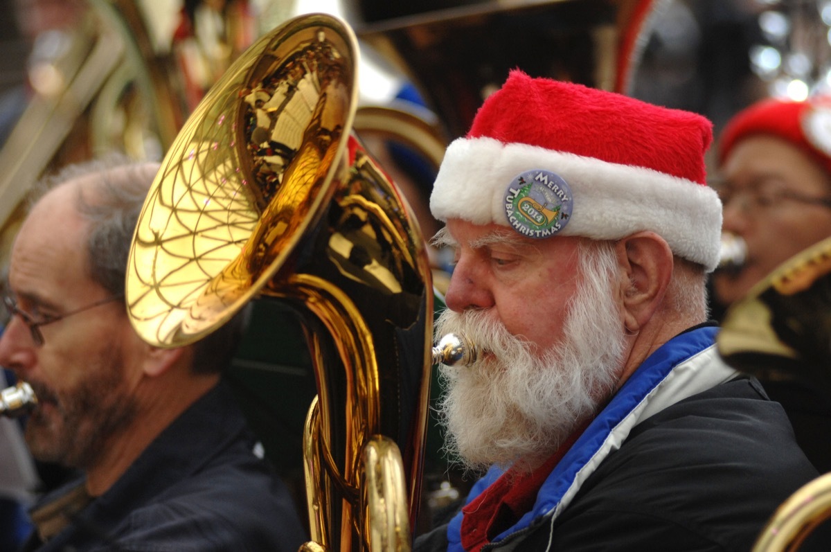 Senior man in Santa Claus hat playing tuba in a band