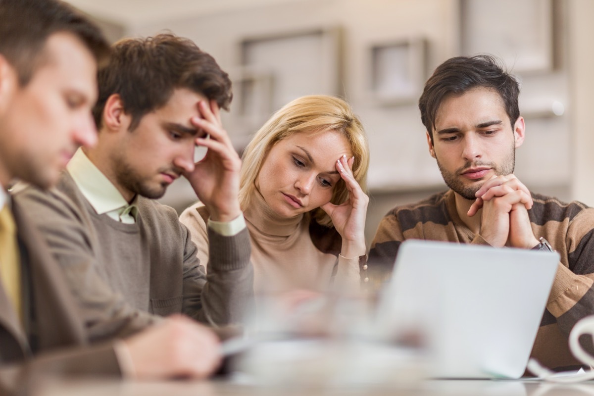 Small group of worried business people using wireless technology and working in the office.