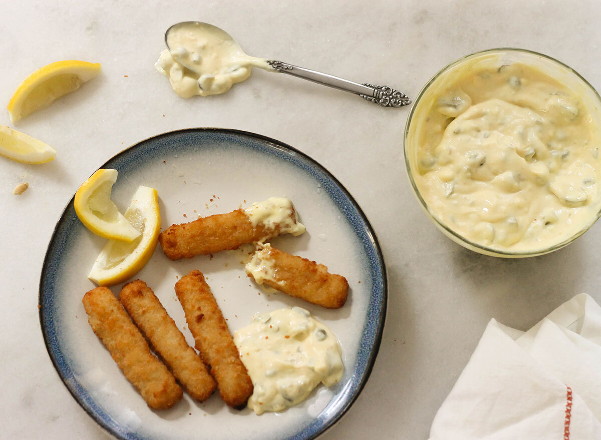 Tartar sauce with fish sticks and lemon wedges on a plate