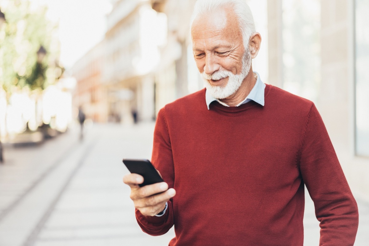 Smart casual senior man texting outdoor on the city street