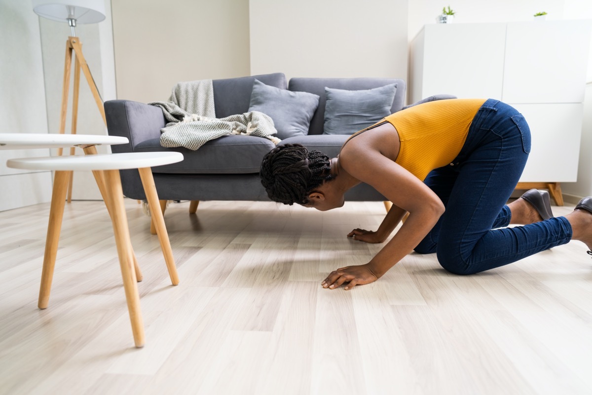 Woman looking under couch for lost item