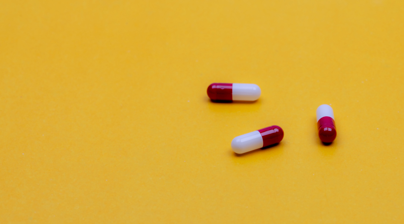 Red and white capsules on a yellow background. 