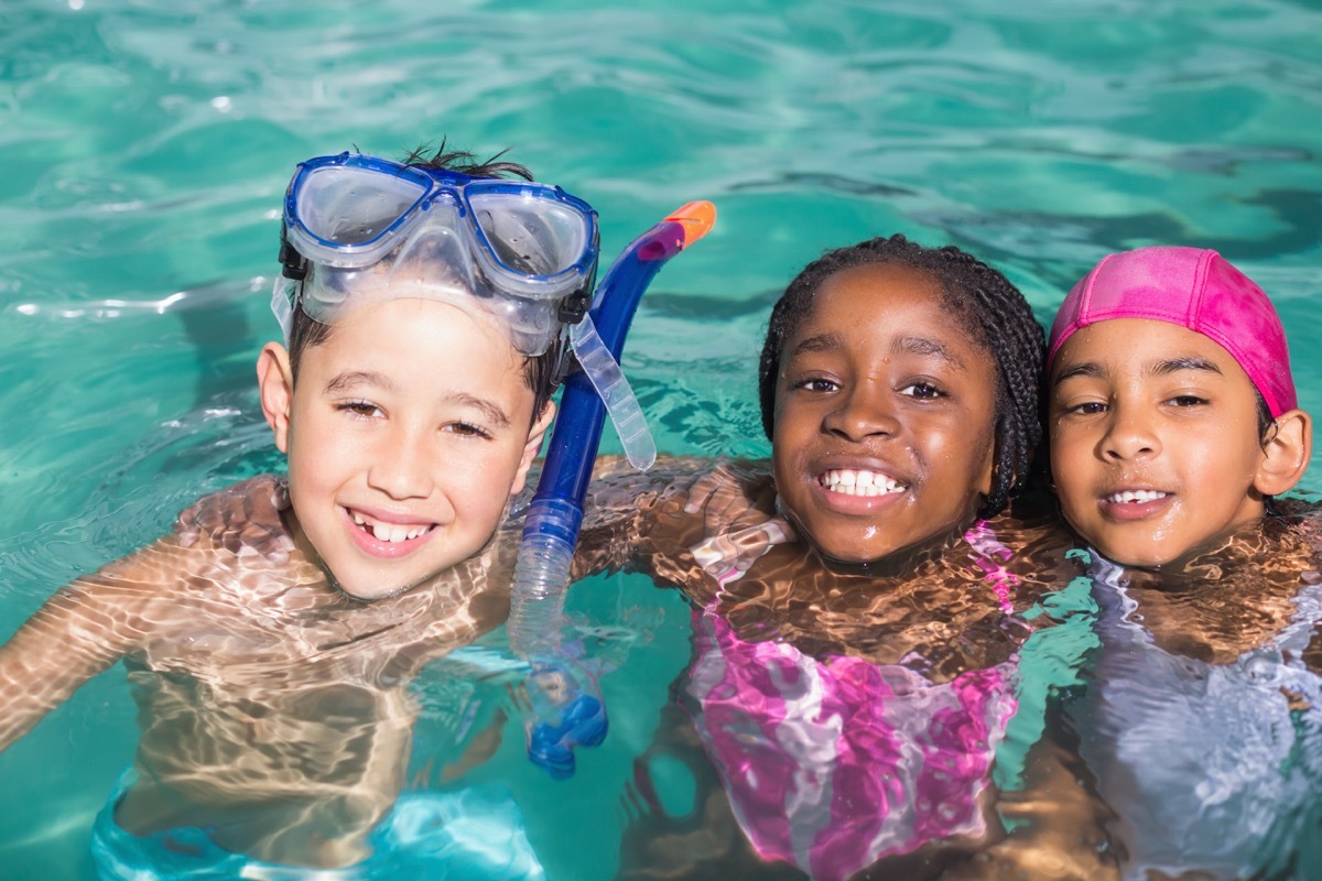 three young children swimming in a pool