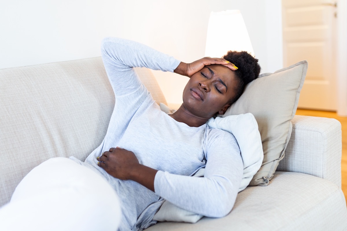  woman suffering from stomachache on sofa at home