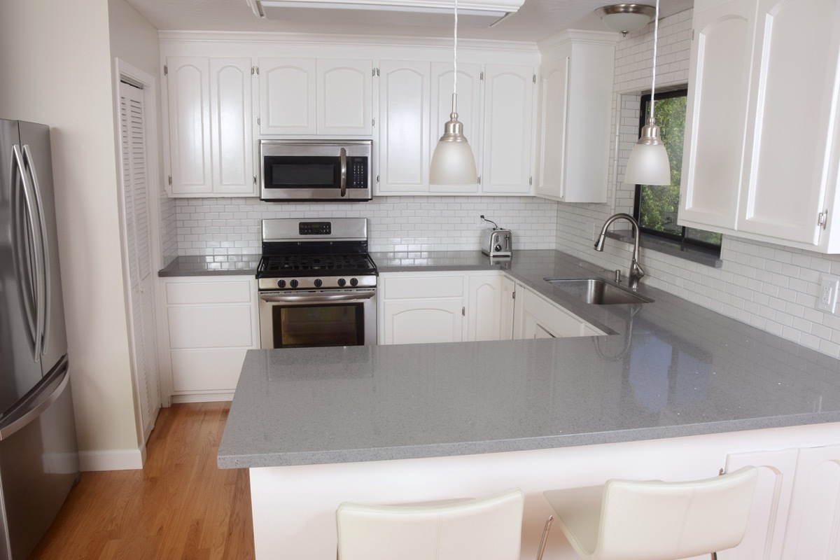 modern kitchen with gray stone counters and white cabinets and subway tile backsplash