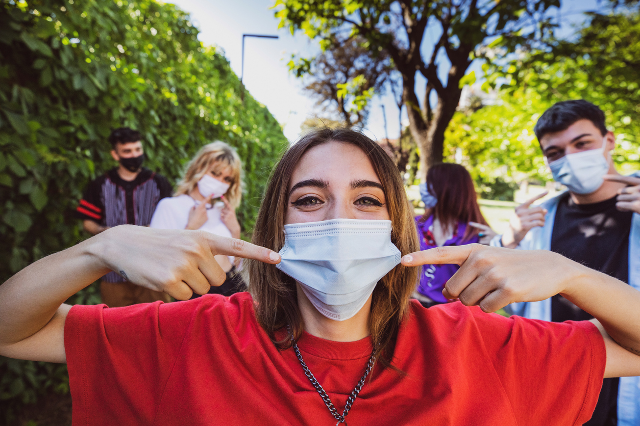 A group of teenagers wearing face masks outdoors.