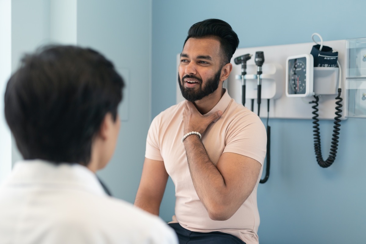 A young man sits up on an exam table while on a visit to the doctor.