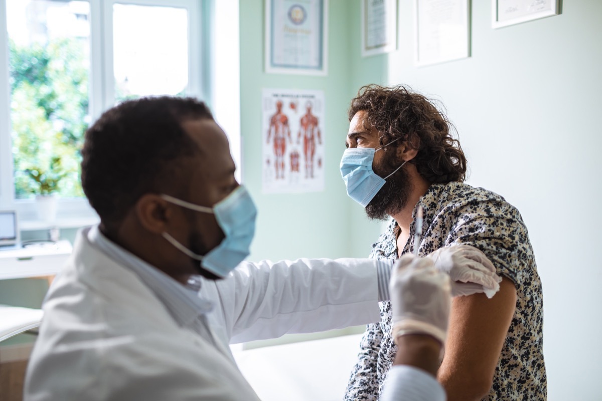 doctor administering covid vaccine to young man