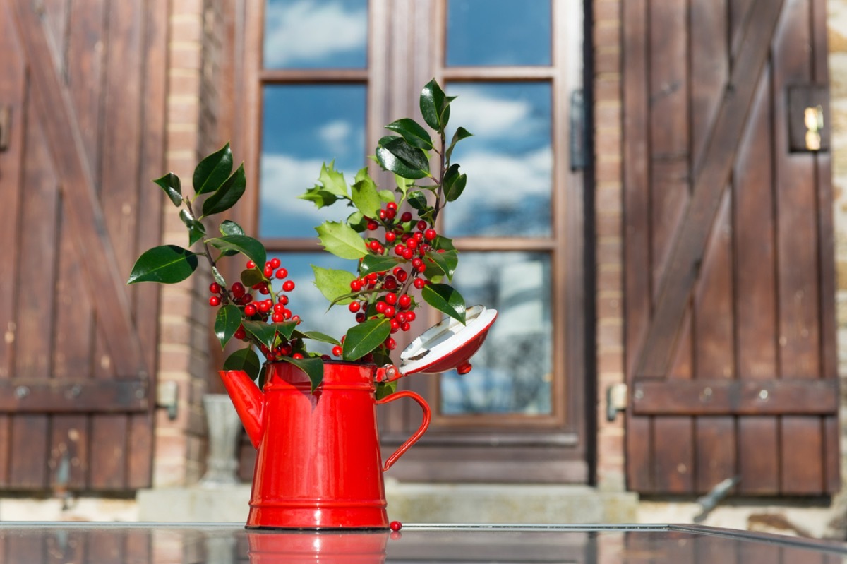 red pitcher full of holly leaves and berries