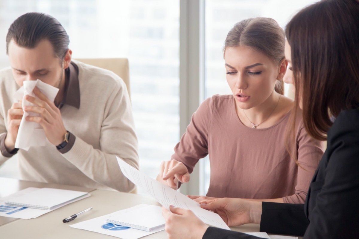 businessman with handkerchief caught flu sitting among colleagues on meeting discussing work issues