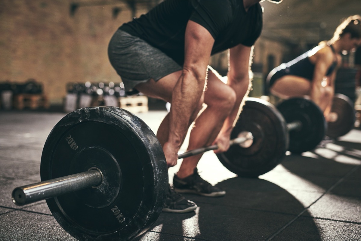 Fit people doing deadlift exercise in gym. Horizontal indoors shot