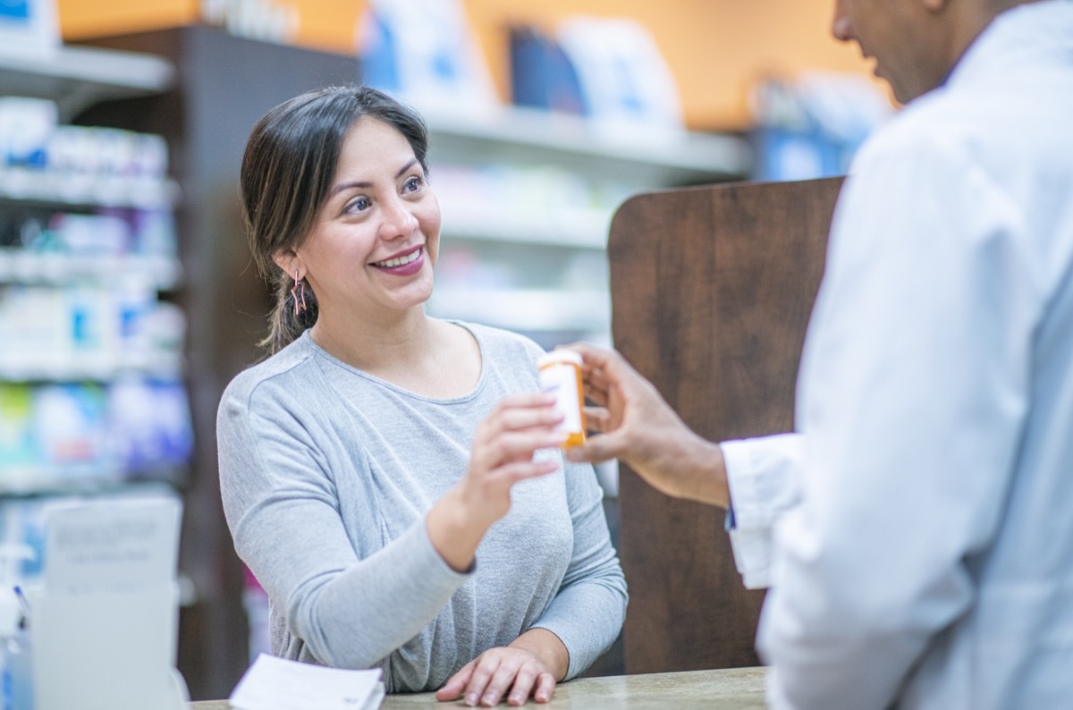 emale customer stands at the desk of a pharmacy filling a prescription.