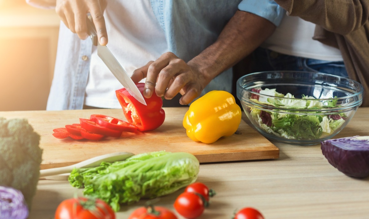 man cutting vegetables for healthy vegetarian salad in kitchen, closeup