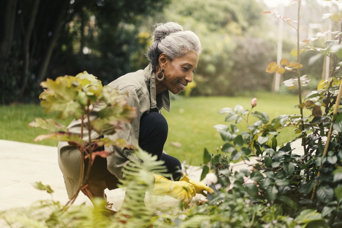 woman crouching and planting her plants in a yard