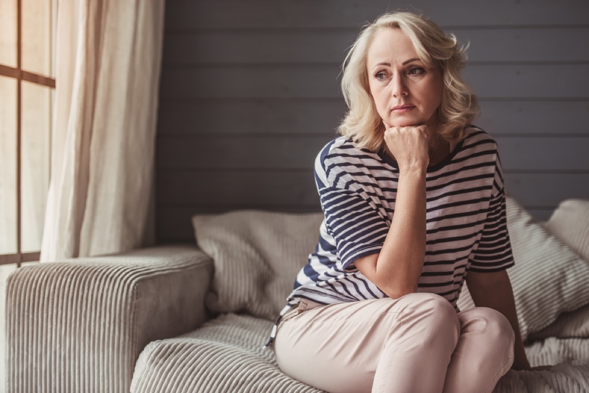 sad older white woman sitting on a couch