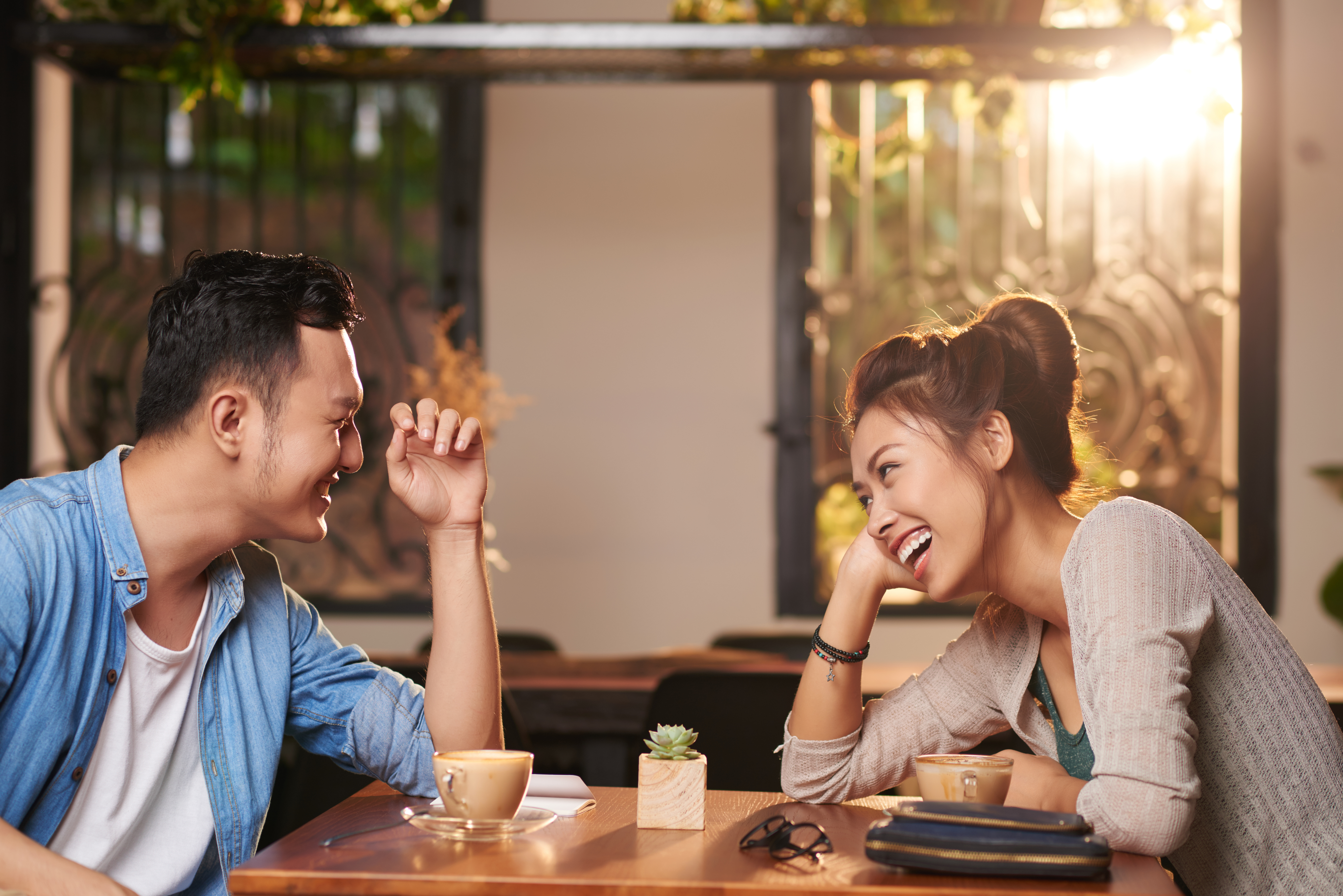 couple laughing over coffee - good questions to ask a guy