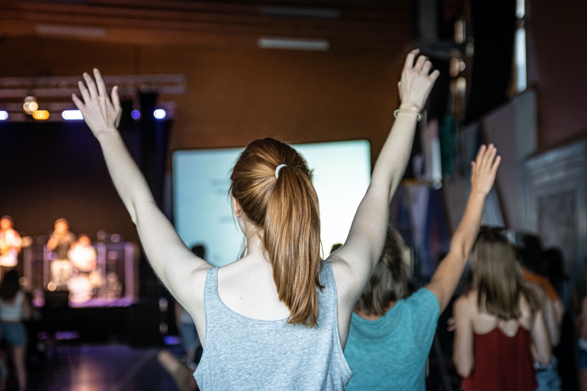 Young woman is worshipping at a service in a church