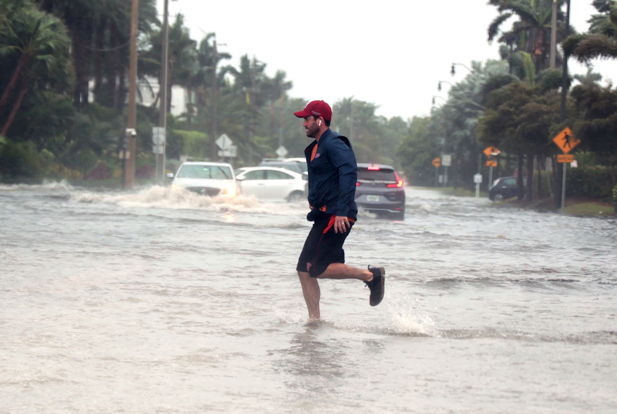 Storm Nicole nears hurricane strength as a man jogs through flooded roads in the Palm Beach area.