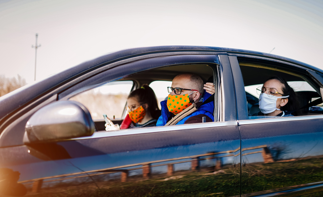 A group of young adults wearing face masks take a ride in a car with the windows rolled down