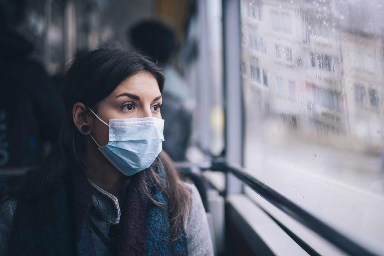 A young woman wearing a face mask riding the bus.