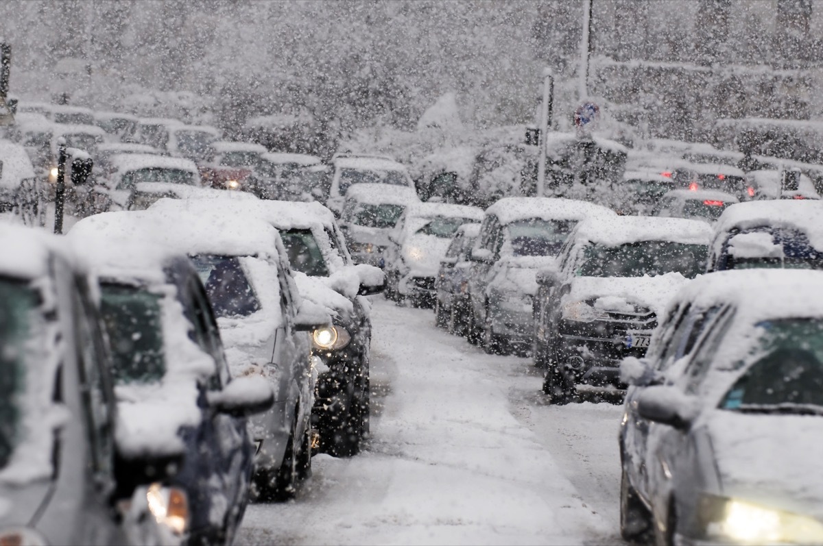 Cars driving on a highway are stuck in traffic because of a snow storm.