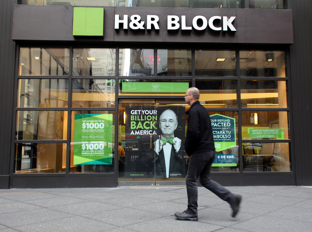 An H&R Block tax services storefront with a customer walking by