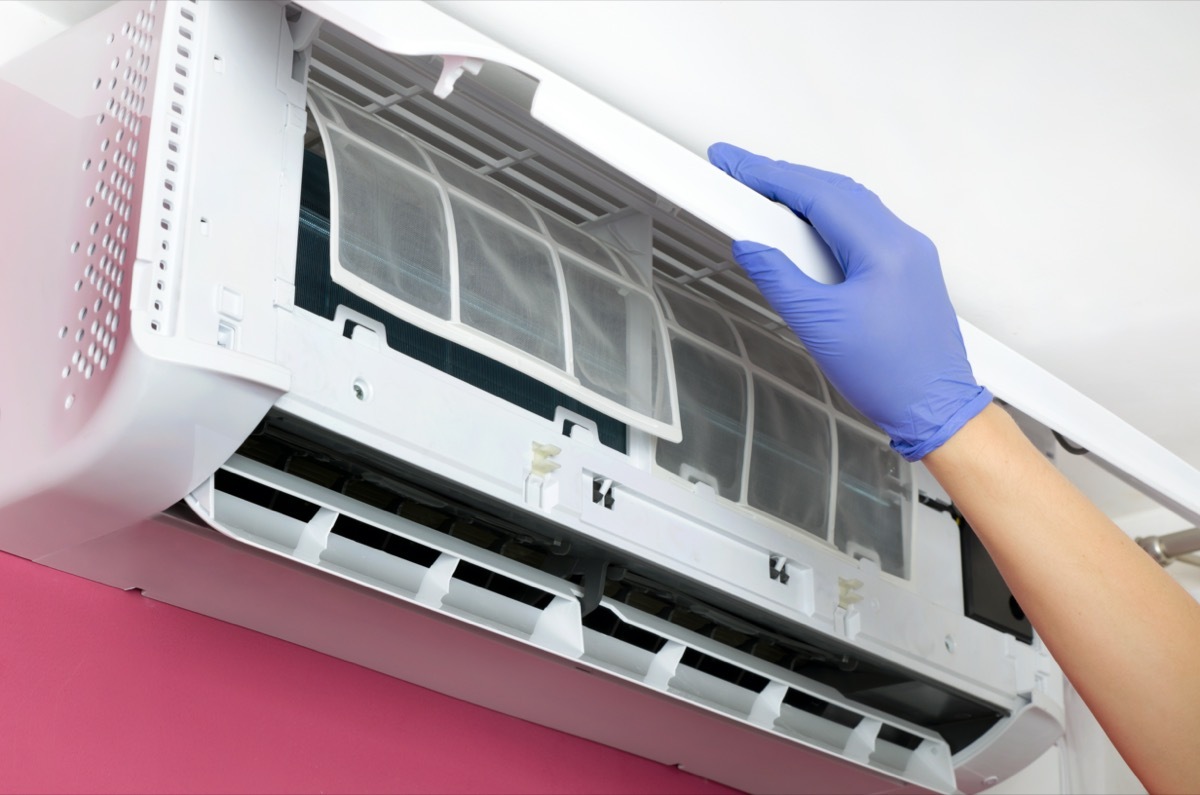 Gloved hand changing an air conditioner filter