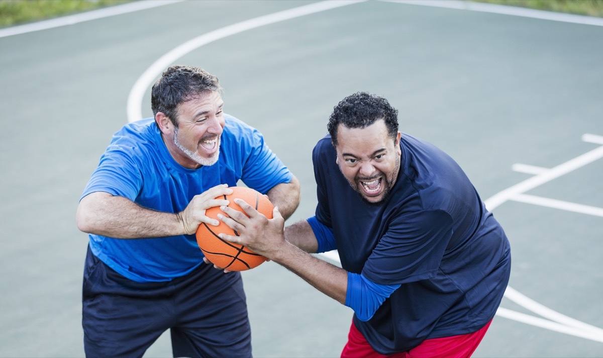 middle aged white man and middle aged black man playing basketball