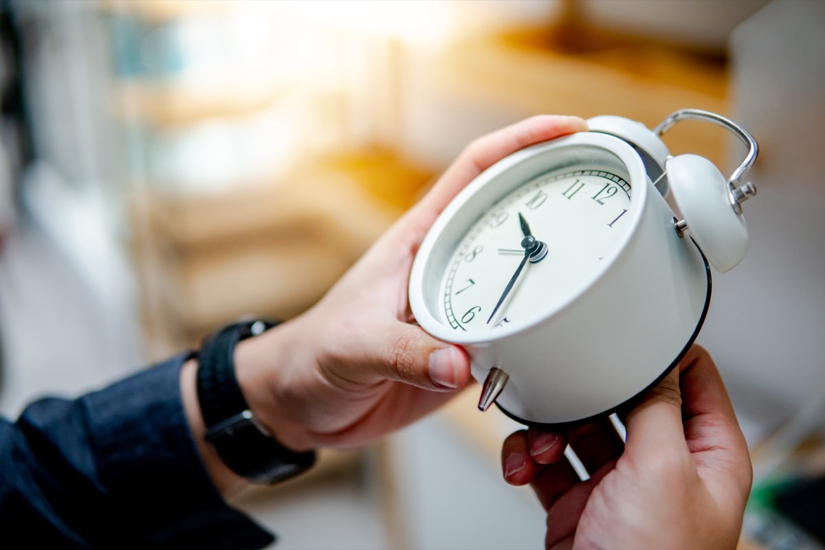 Person changing time on clock