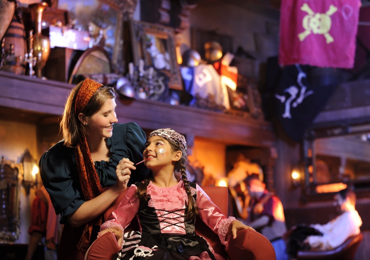 girl putting makeup on little girl at a disney theme park