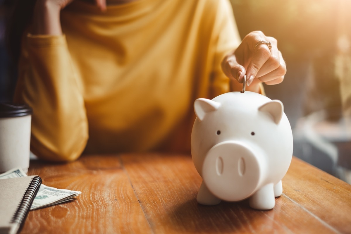 woman hand putting money coin into piggy for saving money wealth and financial concept.