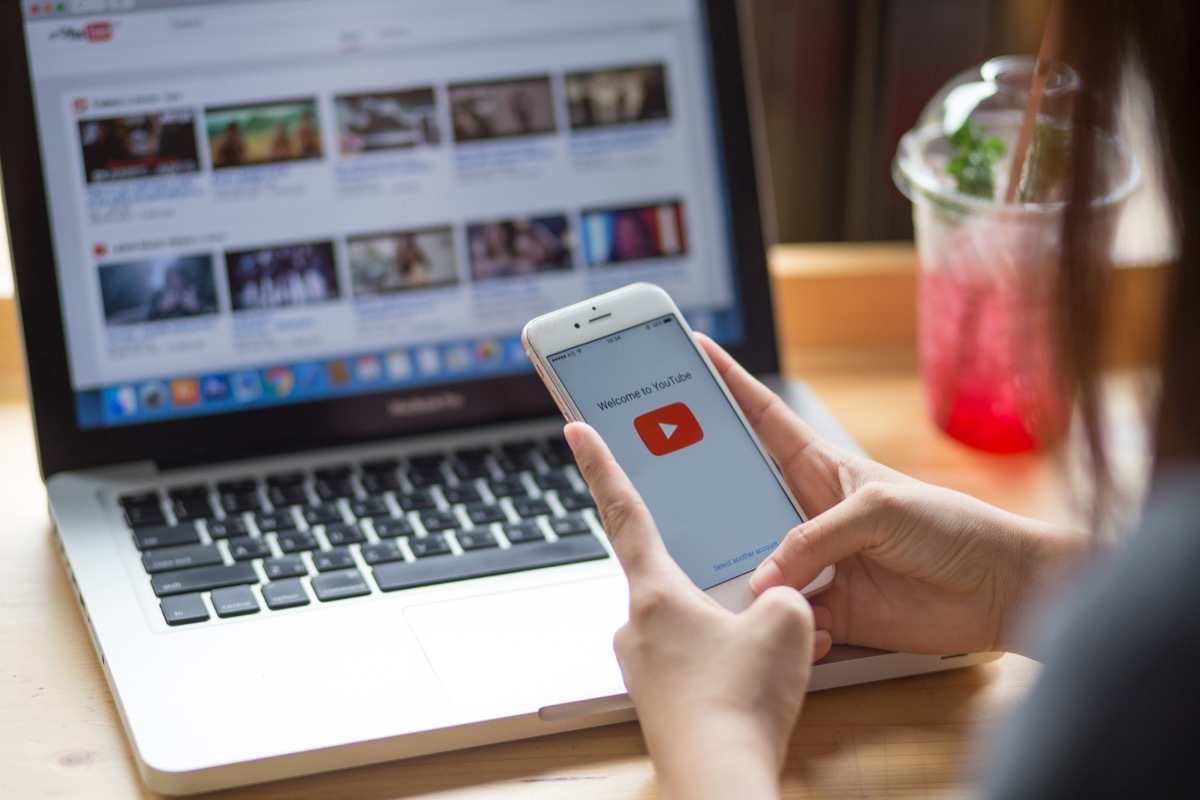 Woman holding iPhone with video service YouTube on the screen