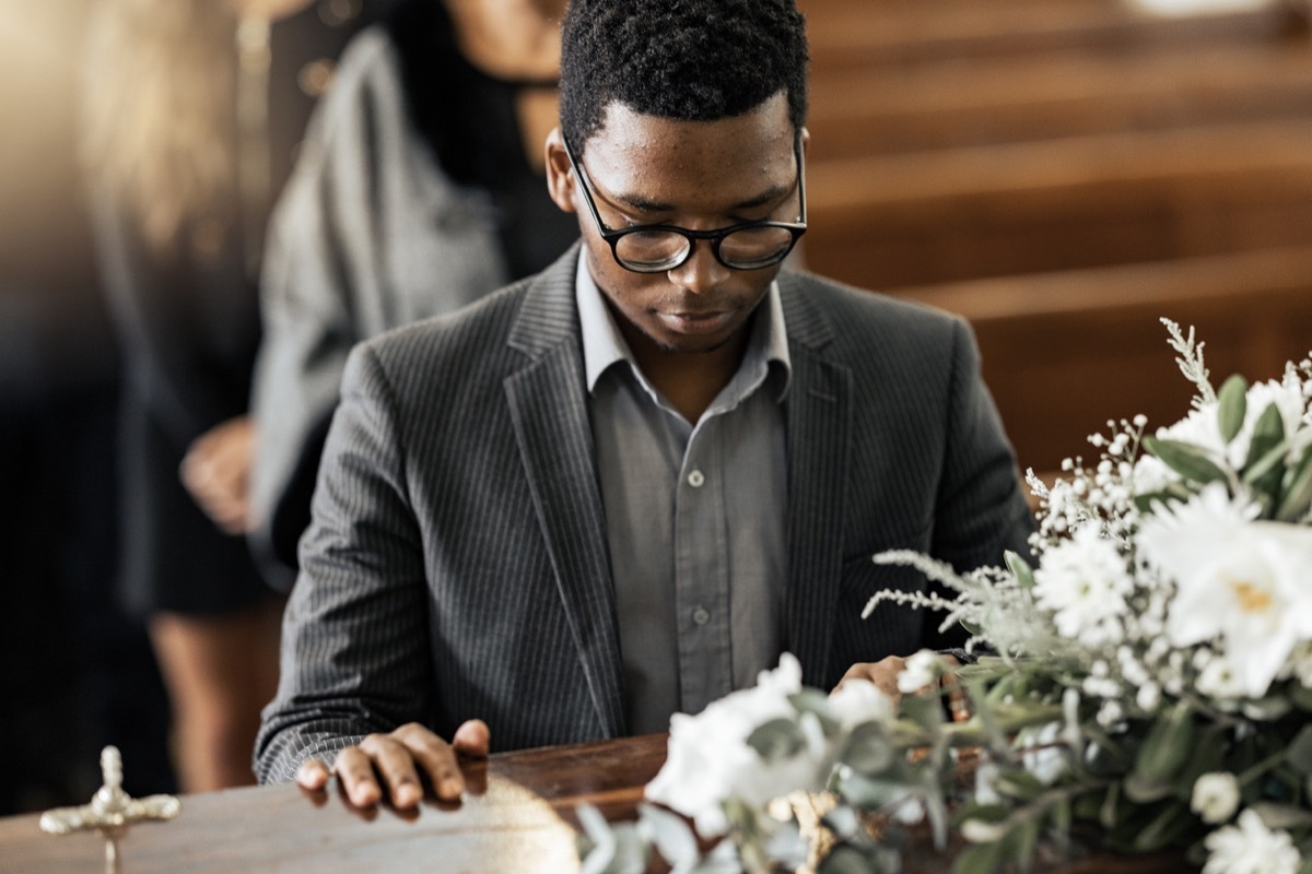 Funeral coffin, death and man sad, grieving and mourning loss of family, friends or dead loved one. Church service, floral flowers and person with casket, grief and sadness over loss of life