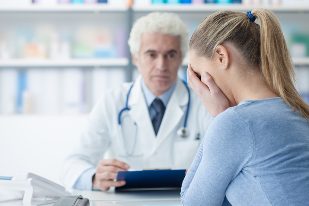 female patient receives bad news with older male doctor