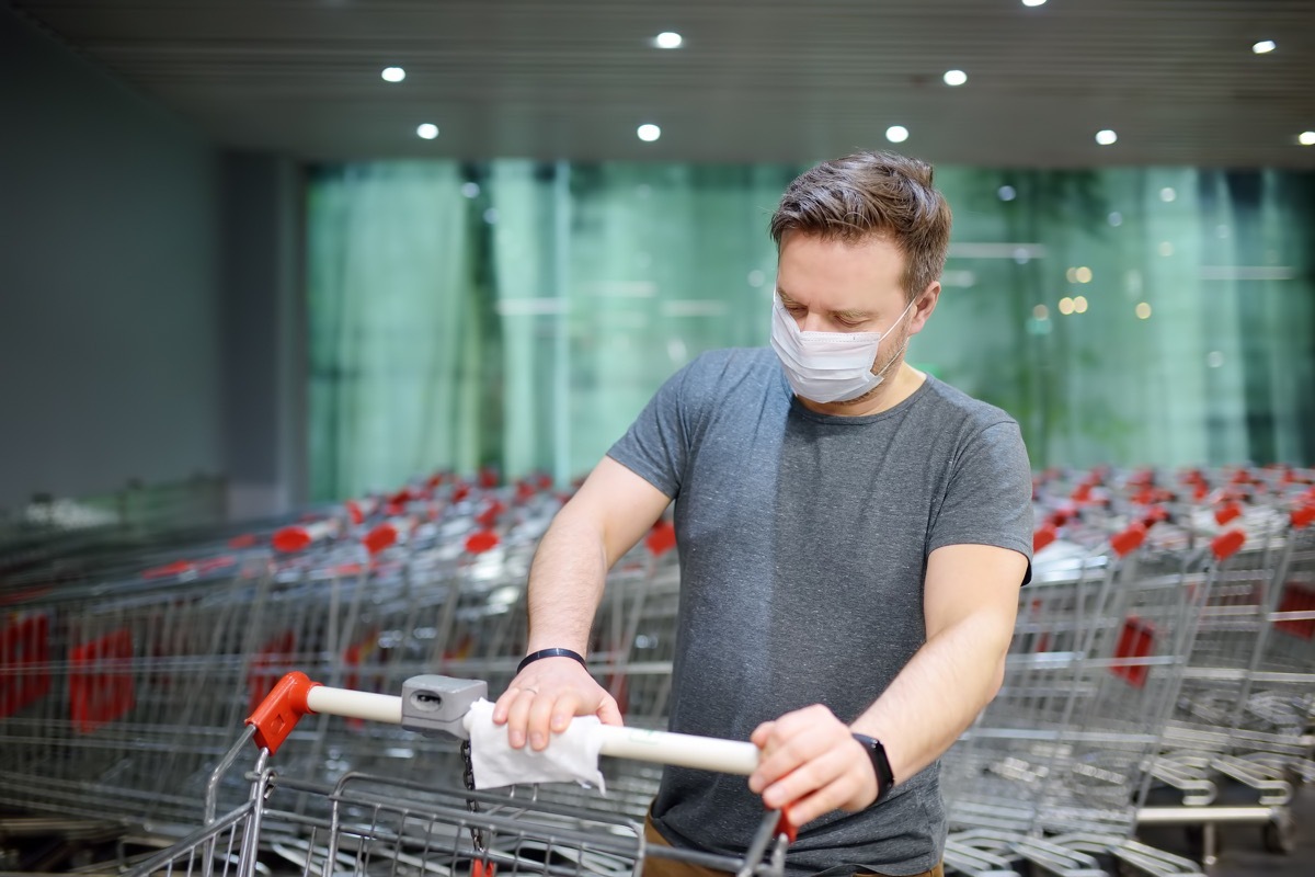 white man wiping down shopping cart